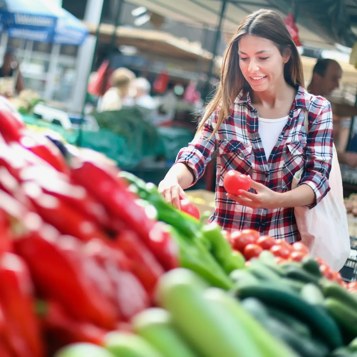 A cheerful shopper with reusable bags at a farmer’s market
