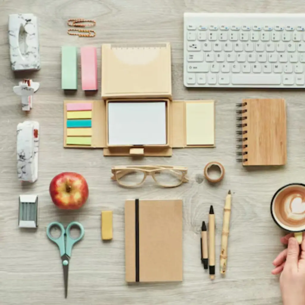 A flat lay of sustainable work tools like notebooks, reusable water bottles, and bamboo pens
