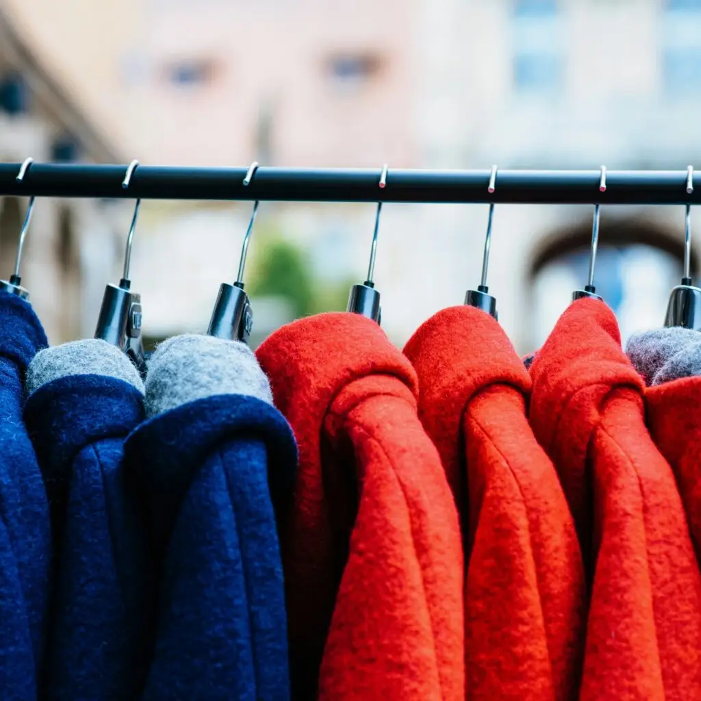A shopper browsing through a rack of jackets in the summer sun