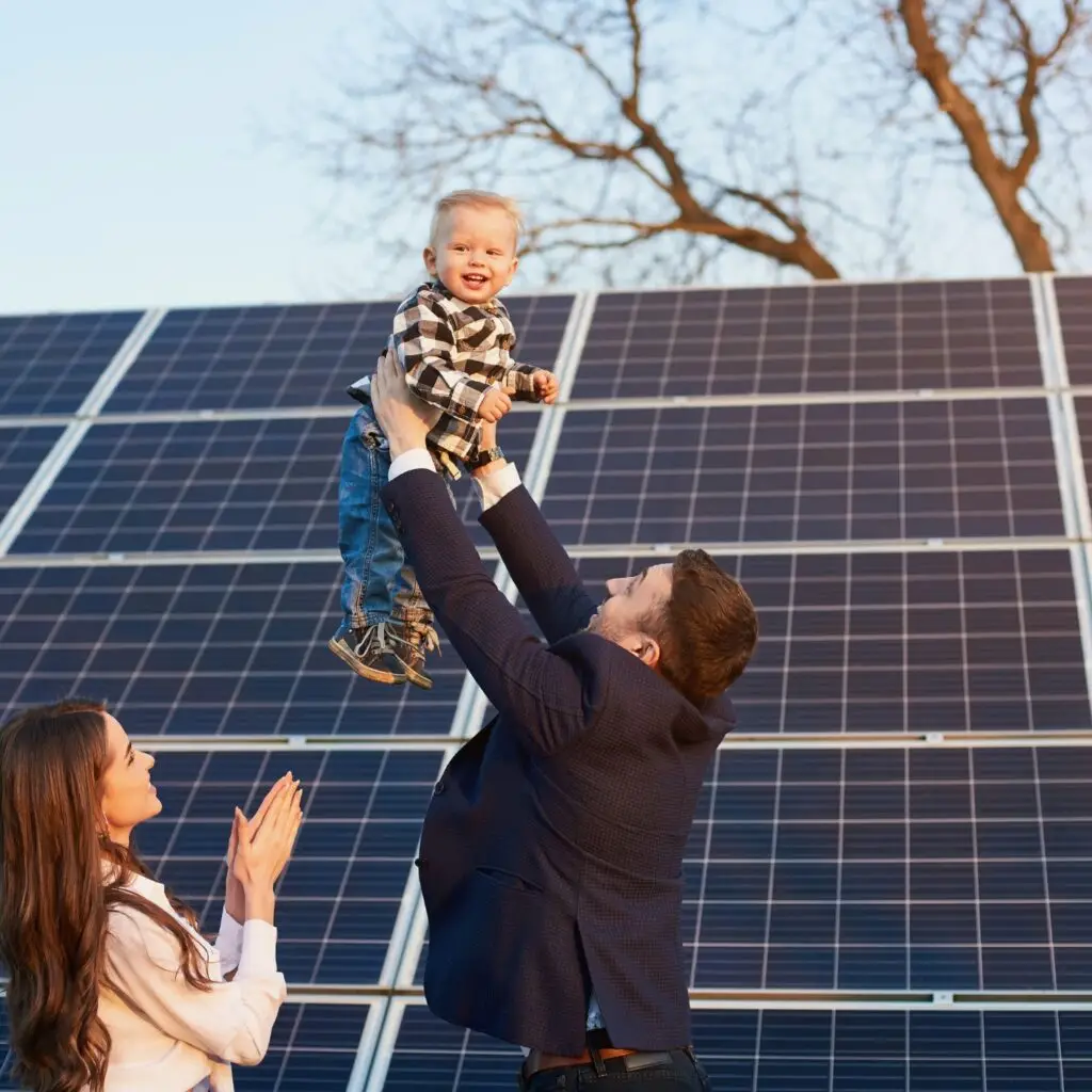 Smiling family standing proudly next to their solar-equipped homes.