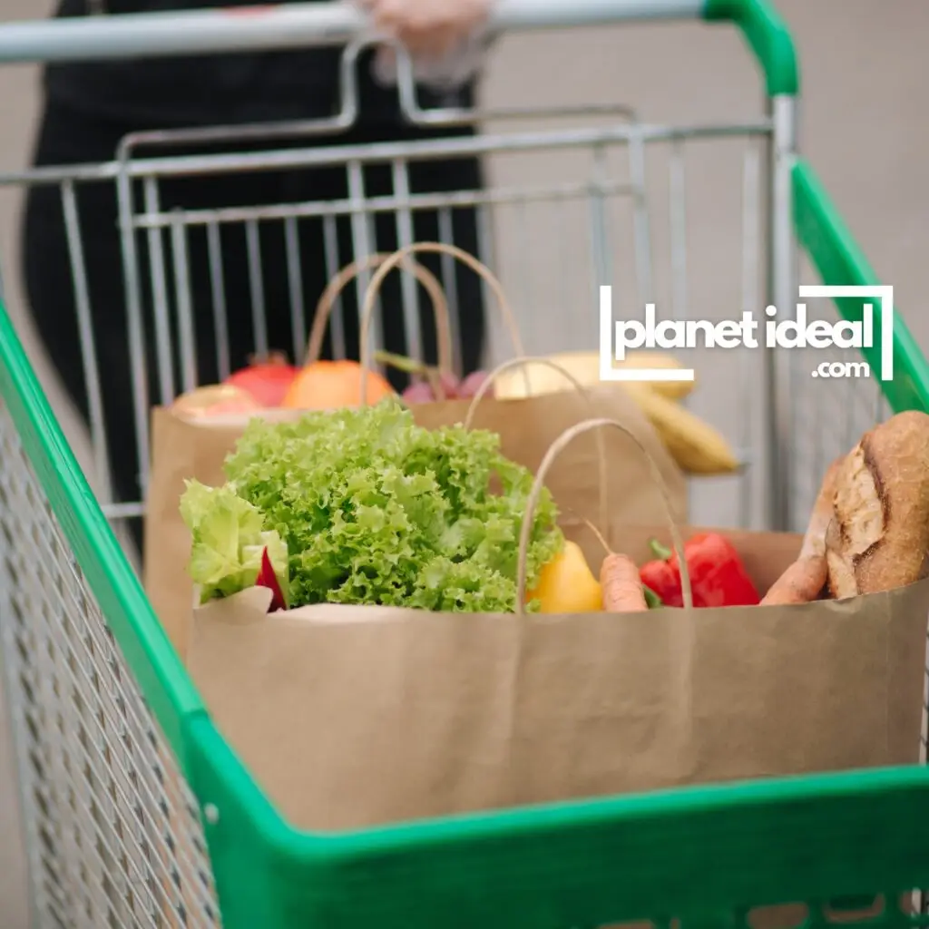 A grocery cart filled with fresh produce, bread, and other staples.