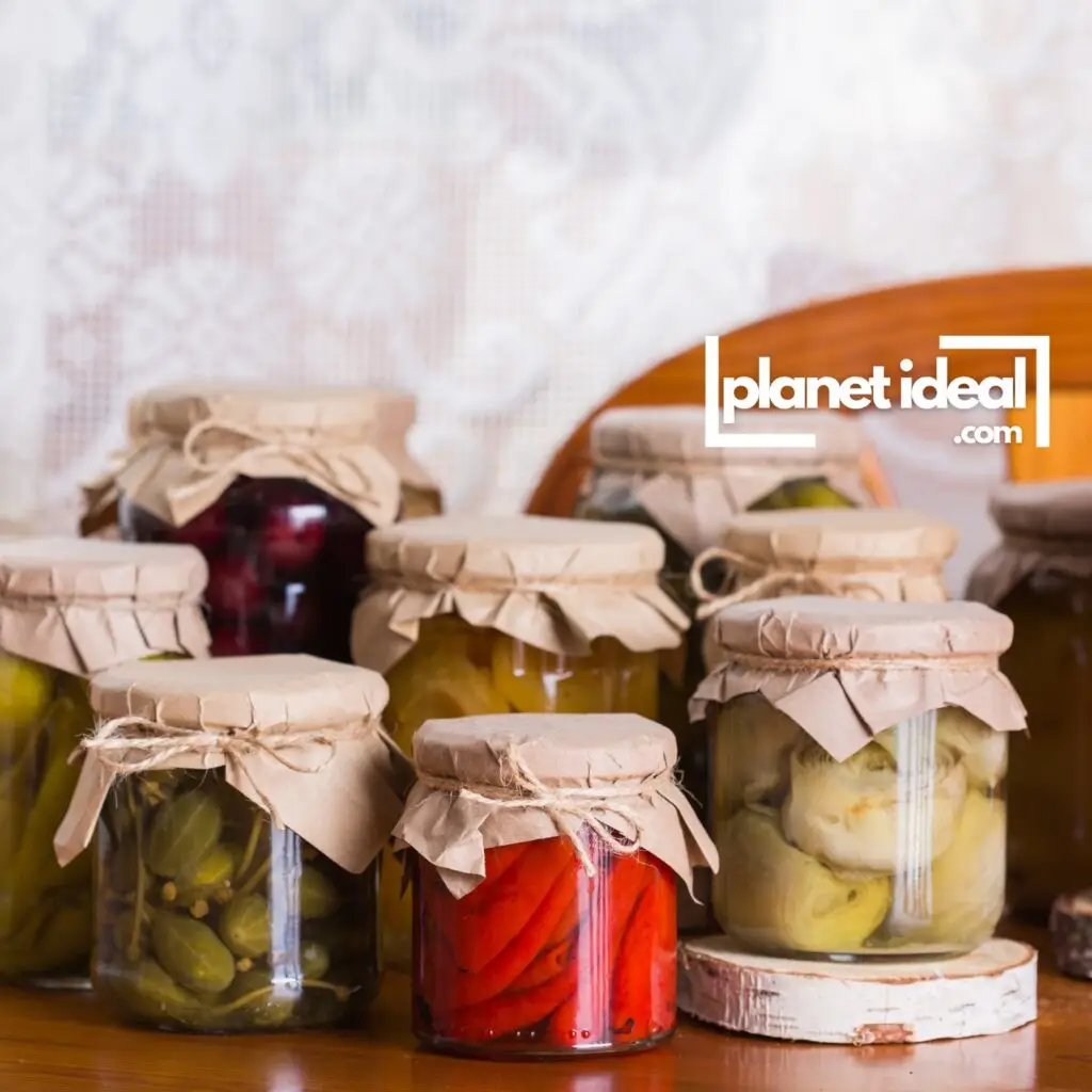 Mason jars filled with vibrant homemade pickles and jams, lined up on a kitchen counter.