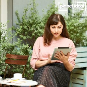 reading a news article on a tablet while sitting in a park